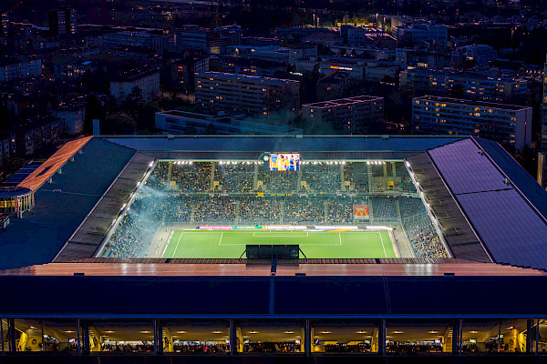 Close aerial view of Wankdorf Stadium showing the pitch, stands, and surrounding residential buildings in evening light.